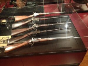 Vintage rifles displayed in glass case at Powder & Lead. Antique firearms collection with historical weapons perfect for firearm enthusiasts and history buffs.