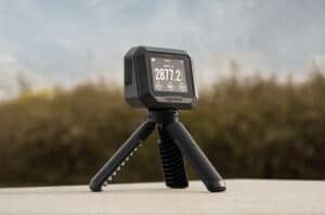 Garmin Xero C2 Chronograph deployed on tripod at an outdoor shooting range displaying velocity readings