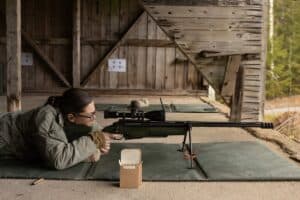 Shooter in prone position with scoped precision rifle on bipod at long-range rifle range