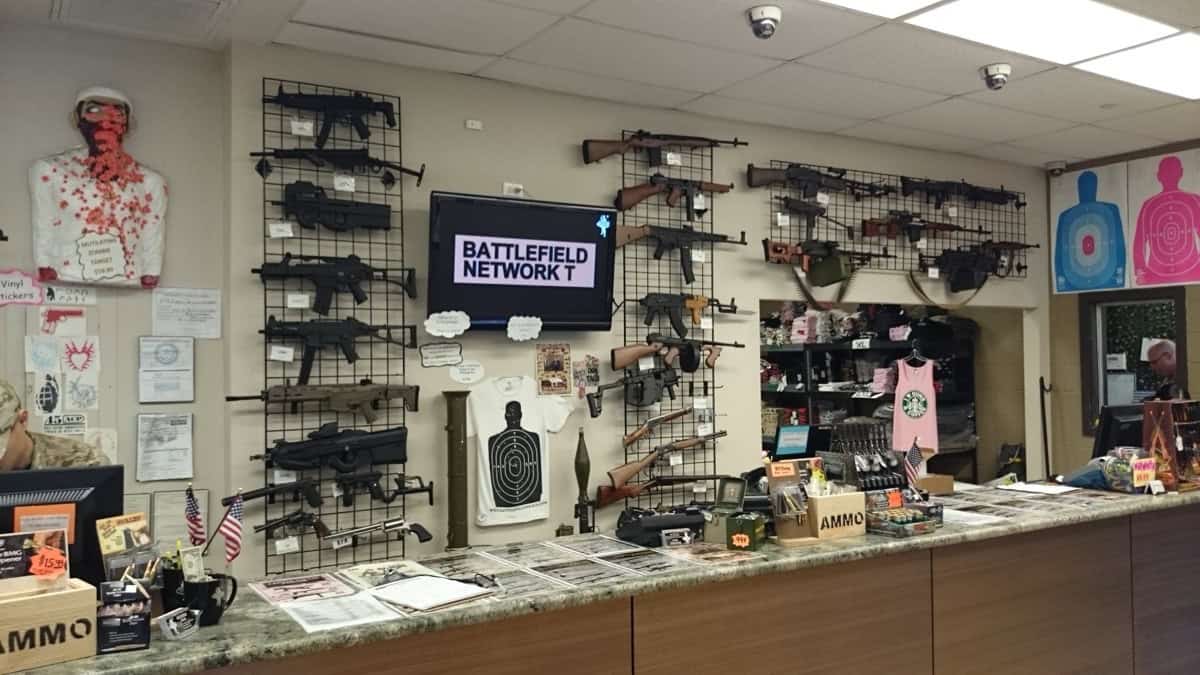 Interior of a gun shop showing firearms on wall display and counter — your first stop when learning how to buy a suppressor